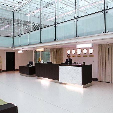 Dubai International Terminal Hotel Exterior foto The photo depicts a modern hotel lobby with a sleek and minimalist design. There is a reception desk made of dark wood and marble, situated in the center of the lobby. A staff member is standing behind the desk, attending to guests. The lobby feature