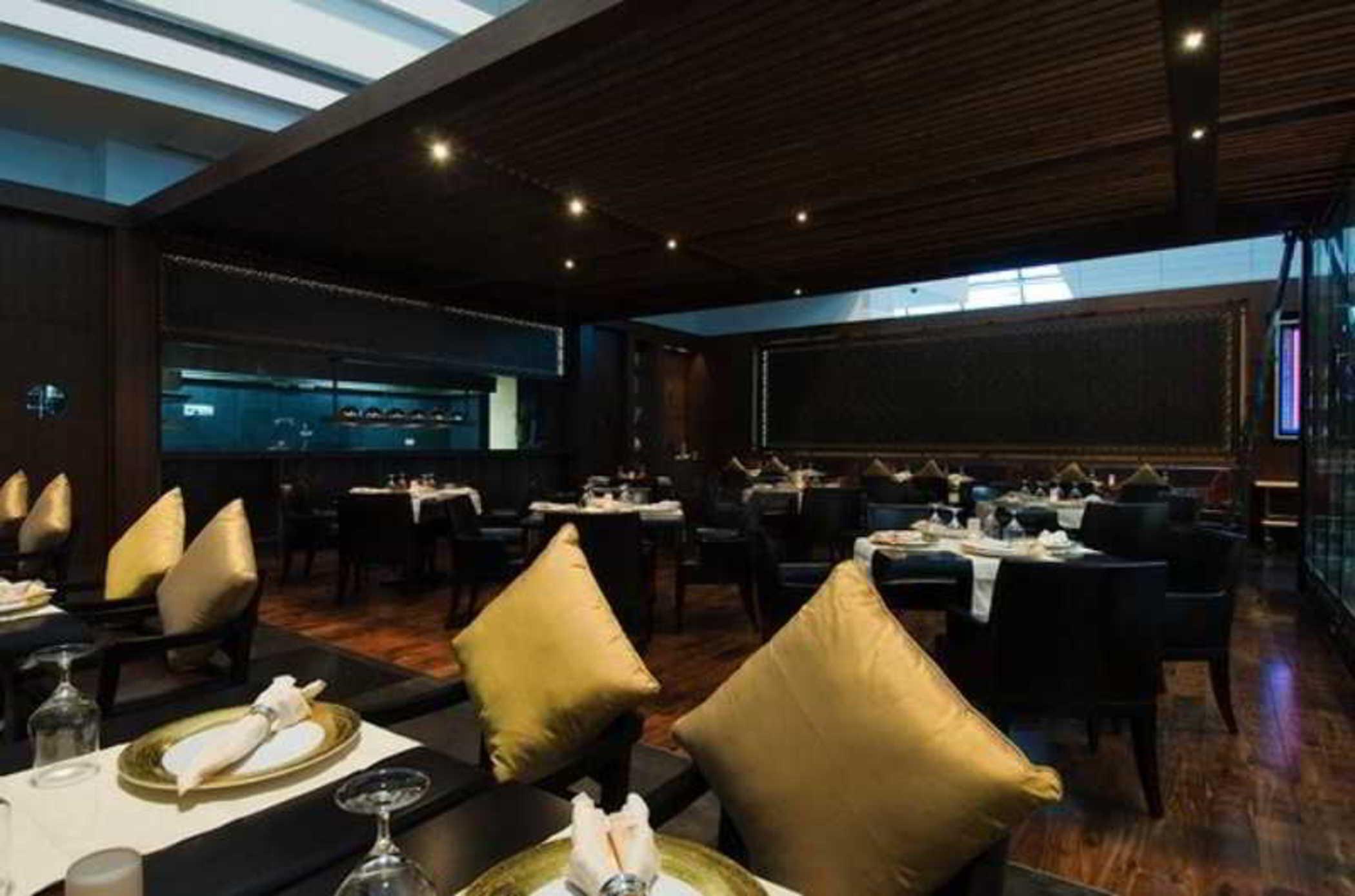 Dubai International Terminal Hotel Restaurante foto The photo depicts a modern restaurant interior. It features a spacious dining area with elegant wooden paneling and a contemporary design. The tables are neatly set with white tablecloths and elegant dishware. There are black chairs, some adorned wit