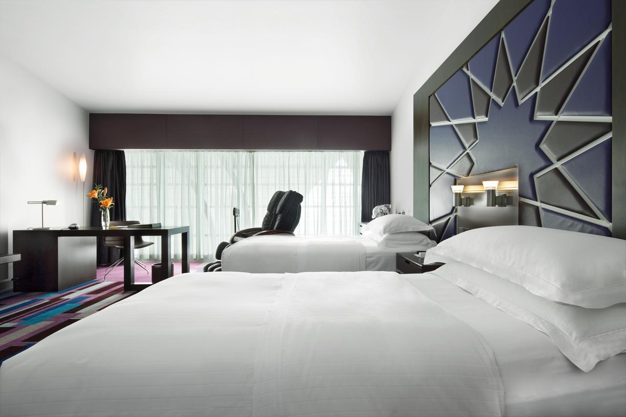 Dubai International Terminal Hotel Exterior foto The photo shows a modern hotel room featuring two beds with white linens. There's a large window with sheer curtains that allows natural light to fill the space. One bed is positioned next to a stylish wall design with a geometric pattern. A small de