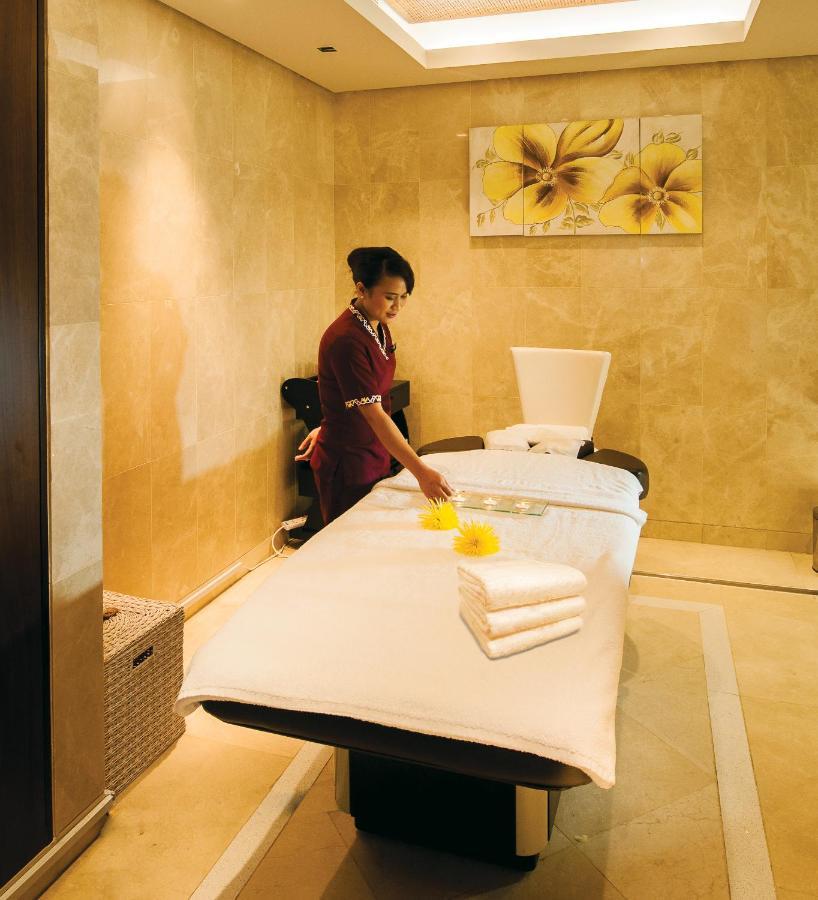 Dubai International Terminal Hotel Exterior foto The photo shows a spa setting with a massage table in a soothing environment. A staff member, dressed in a uniform, is preparing the table for a treatment. There are neatly folded towels placed on the table, and a tray with some items, possibly for a